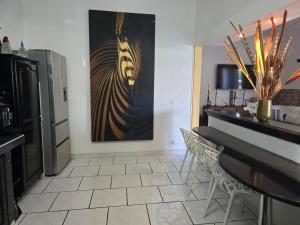 a kitchen with a table and a painting on the wall at Villa Chelsy in Capesterre-Belle-Eau