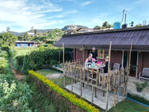 a family sitting at a table outside of a house at Keshiya Holiday Home in Nuwara Eliya