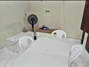 a room with white chairs and a table with a fan at Casa próximo a praia in Salvaterra
