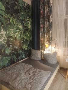 a bed with two pillows and a wall with plants at Ku'damm Taler's Central - Self Check In in Berlin