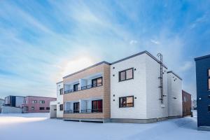 a white building with snow on the ground at Hills Niseko 106 in Niseko