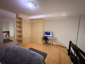 a bedroom with a bed and a desk with a computer at Apartamento Jaragua do sul in Jaraguá do Sul