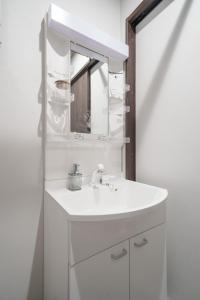a white bathroom with a sink and a mirror at Hills Niseko 106 in Niseko