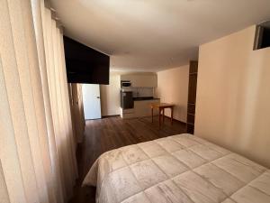 a small bedroom with a bed and a kitchen at Gran Estancia Vallecito in Arequipa