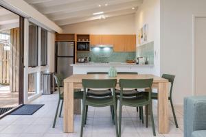 a kitchen and dining room with a wooden table and chairs at Sandpiper 11 in Smiths Lake +15 photos