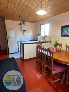 a kitchen and dining room with a table and a refrigerator at cabañas canemar in Hueyilemu +9 photos