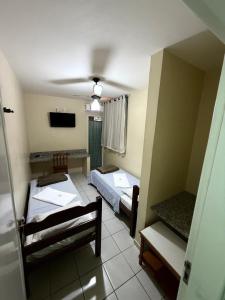 a room with two beds and a flat screen tv at Modenesi Hotel in Linhares