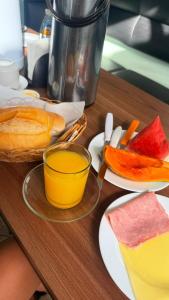 a wooden table with plates of fruit and a glass of juice at Modenesi Hotel in Linhares