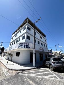 a hotel with a car parked in front of it at Modenesi Hotel in Linhares