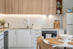 a kitchen with white cabinets and a table with chairs at Sandpiper 4 in Smiths Lake