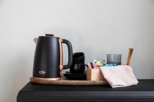 a coffee pot on a wooden cutting board on a table at The Deco Retreat in Hawera
