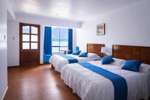two beds in a hotel room with blue pillows at Mi Hacienda Pacucha in Andahuaylas +28 photos
