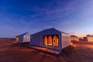 two small buildings in the desert at night at Luxury Camp Sahara in Merzouga