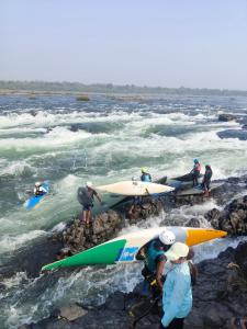 a group of people with surfboards on the rocks in the water at Shivakashi Homestay in Maheshwar