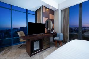 a bedroom with a bed and a desk with a television at Aston Inn Mataram in Mataram