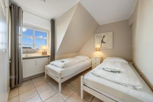 two beds in a small room with a window at LH Dünenblick Wohnung 9 in Wenningstedt