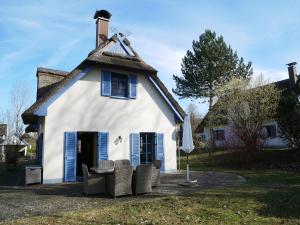 a house with a thatched roof with chairs in front at Mohnblume in Am Schwarzen Busch