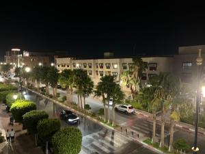 a city street at night with cars and palm trees at Résidence Meublée Jihane in Laayoune