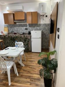 a kitchen with a white table and a white refrigerator at Résidence Meublée Jihane in Laayoune