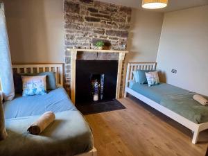 two beds in a room with a fireplace at Ceol na Mara in Berriedale