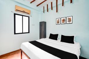 a bedroom with a white bed with black pillows at HOTEL O MID STAR in Sakardarā