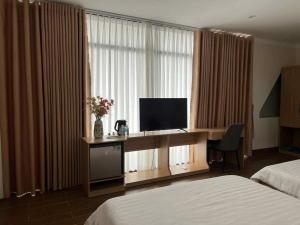a hotel room with a desk with a television at Huỳnh Nga Măng Đen Hotel in Kon Plong