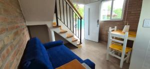 a living room with a blue couch and stairs at Duplex Playa Mansa in Mina Clavero