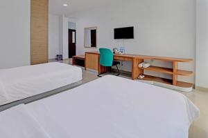 a bedroom with two beds and a desk with a computer at Hotel Training Center UIN Mataram in Mataram