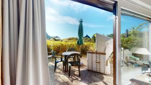 a patio with a table and chairs and an umbrella at Vierfuss 1A in Hörnum