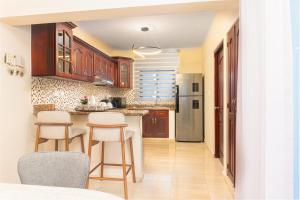 a kitchen with wooden cabinets and bar stools at Villa Lionisia in Puerto Plata