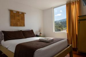 a bedroom with a bed with a large window at HOSTAL DEL RÍO in Ibarra