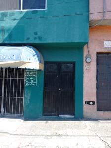 a green building with a black door and a sign at Casa Capuchina in Querétaro