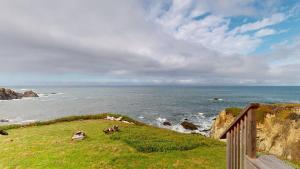 a view of the ocean with cows on a hill at Tideaway Private Hot Tub and Expansive Ocean View in Fort Bragg