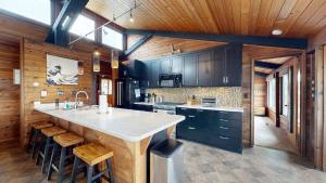 a kitchen with black cabinets and a counter with bar stools at Tideaway Private Hot Tub and Expansive Ocean View in Fort Bragg