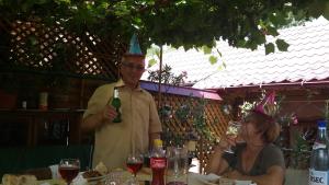 a man wearing a party hat and holding a bottle of wine at Casuta dintre dealuri in Vlădeşti +16 photos