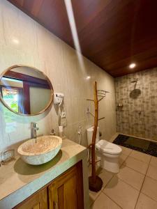 a bathroom with a sink and a toilet and a mirror at Cempaka Kembar Guest House Ubud in Ubud