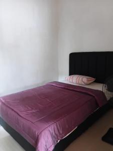 a bed with a purple comforter and two pillows at Adah 786 Villa Syariah in Krian