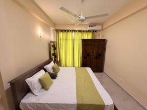 a bedroom with a large bed with a yellow curtain at Wellness Residency in Colombo