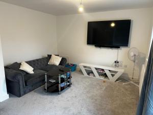 a living room with a black couch and a flat screen tv at Dzingai Home in Newport +3 photos