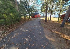 a road leading to a red barn in the woods at Loons Landing Legacy in Saint Germain