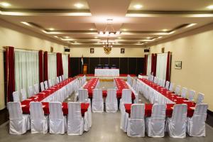 un salón de banquetes con mesas y sillas blancas y rojas en Rudang Hotel & Resort Berastagi, en Berastagi