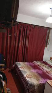 a bedroom with a bed and a red curtain at Triplex waltito in San Clemente del Tuyu