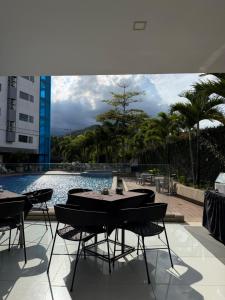 Ein Tisch und Stühle stehen neben einem Schwimmbecken. in der Unterkunft Hotel Blue 66 in Cali