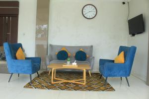 a living room with a couch and two blue chairs at Hotel Mangkuto Syariah in Payakumbuh
