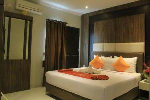 a bedroom with a large white bed with orange pillows at Hotel Mangkuto Syariah in Payakumbuh
