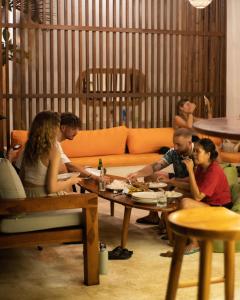 a group of people sitting around a table in a living room at Lost Inn Kuta Capsule Hostel in Kuta Lombok