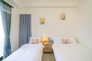 two beds in a room with a window at Sunlight Orchid Rain Homestay in Dongshan