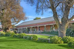 a red brick building with a tree in a park at Lancefield Guest House in Lance Field