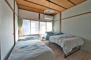 two beds in a room with a window at Hareumi in Tamano