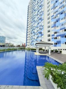 a large swimming pool with a gazebo in front of a tall building at Baan Mai Condo Staycation in Biñan